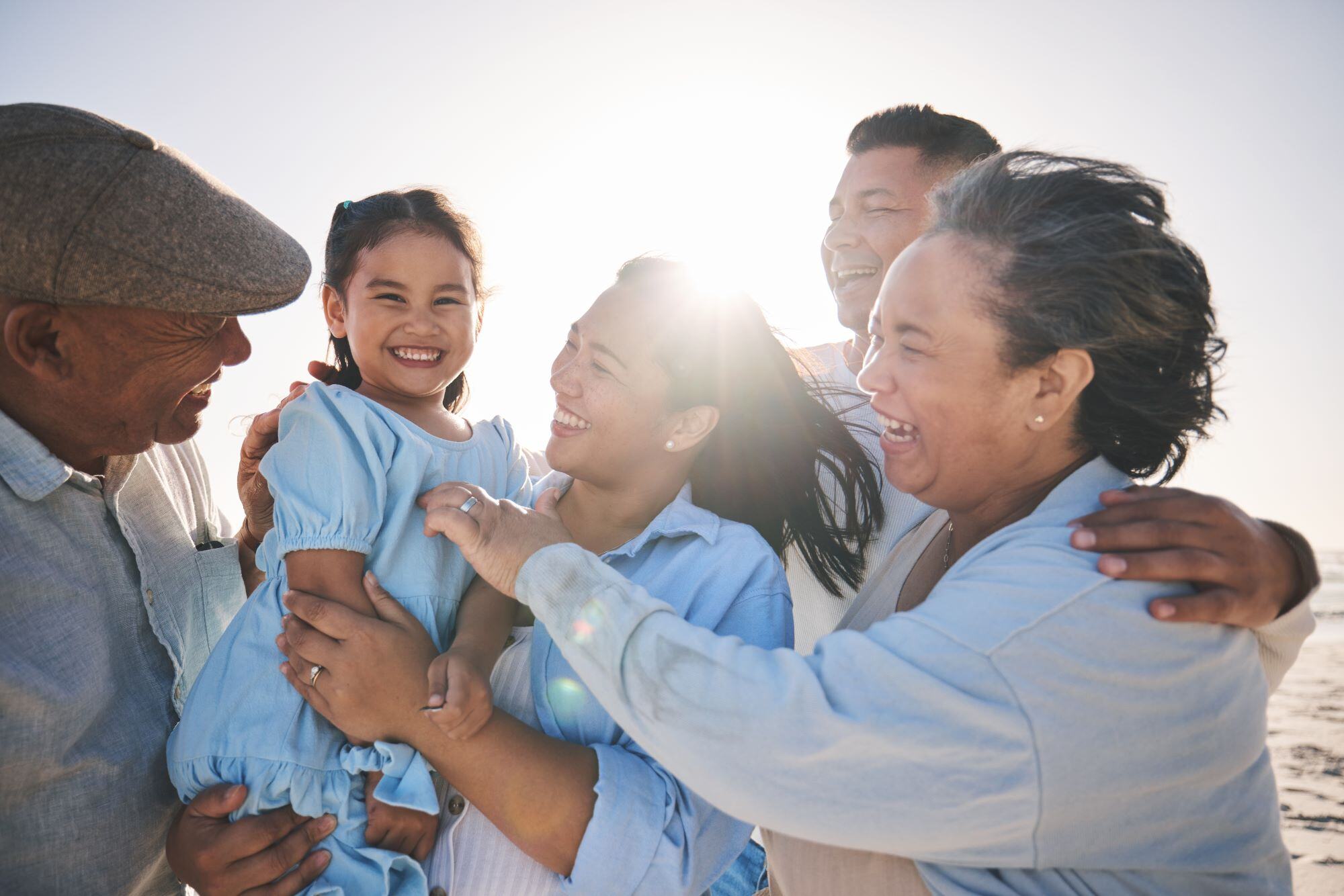 Happy hispanic family - grandparents, parents and young girl, with sun shining from behind them